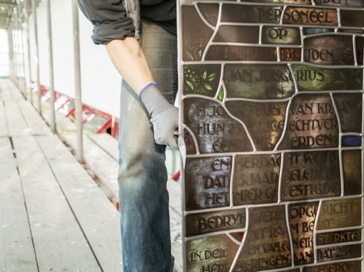 Fotograferen vakmensen: glazenier herplaatst monumentaal gerestaureerd glas-in-lood. I.o.v. Heilijgers Bouw.