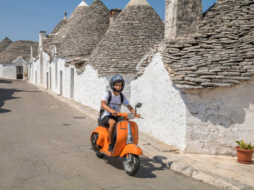 Vespa tussen de historische trulli in Alberobello, Puglia