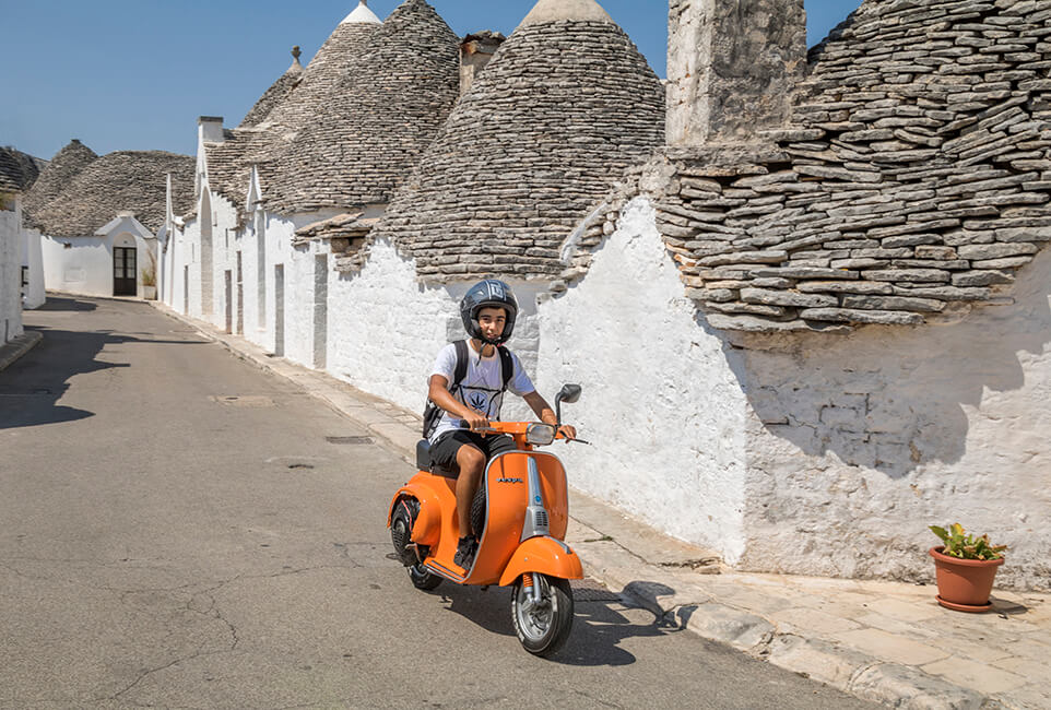 Vespa tussen de historische trulli in Alberobello, Puglia